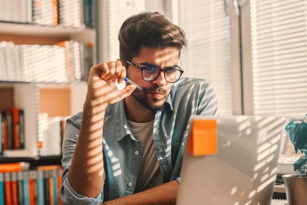 AdobeStock_256401973_Junger Mann nachdenklich am Laptop