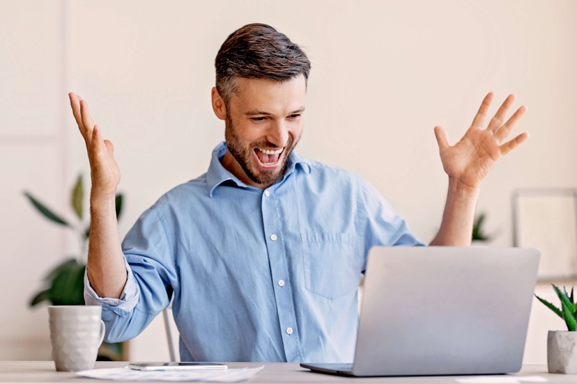 Zufriedener lachender Mann am Computer hat seine Aufgabe erfüllt.